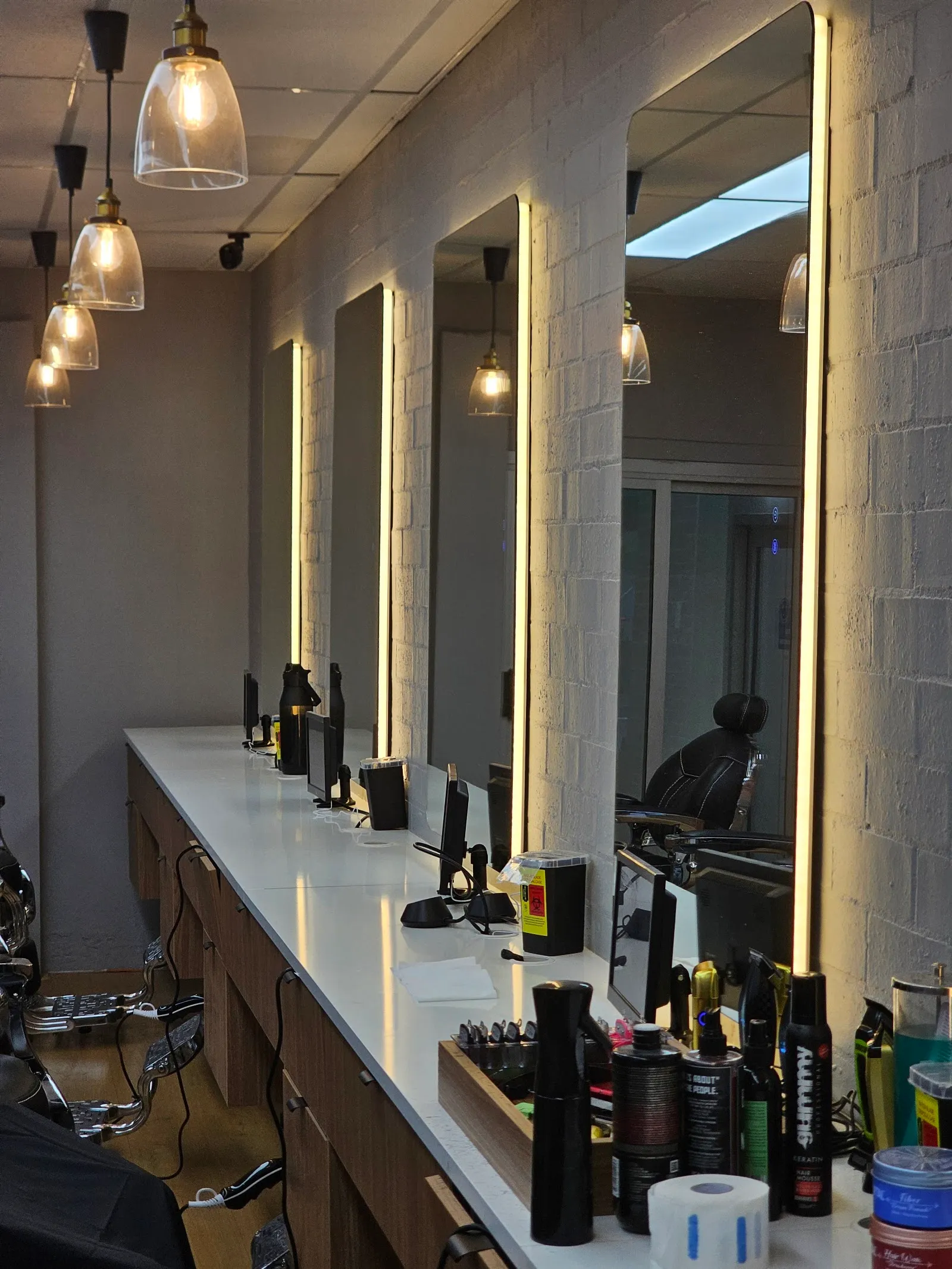 A row of lit mirrors above a long styling bench with products